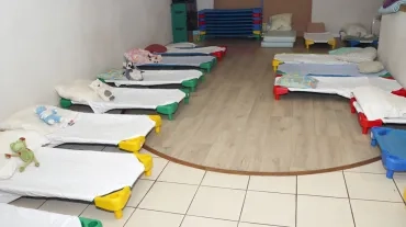 Un salle avec des petits lits équipés de draps et d'oreillers sur lesquels sont disposés une peluche