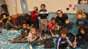 Un groupe d'enfants montrent les morceaux de papier qui vont devenir des briques