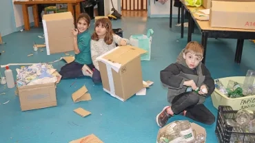 3 enfants fabriquent de grandes boîtes en carton