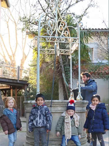 des enfants et un animateur sont devant le puits