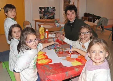 un groupe d'enfants et leur animatrice peignent des flammes de de grandes feuilles en papier