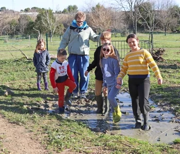 un groupe d'enfant et leur animateur marchent avec leurs bottes  en caoutchouc dans une mare boueuse