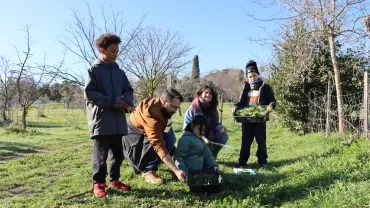 un groupe d'enfant et leurs animateurs coupent de l'herbe