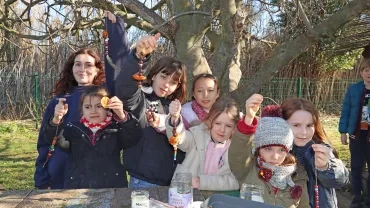 un goupe d'enfants et leur animatrice montrent des guirlandes avec des perles et des rondelles d'agrumes