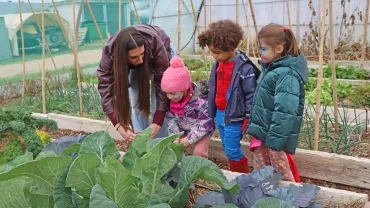 un goupe d'enfants et leur animatrice regarde des plantations dans la serre