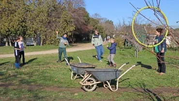 un groupe d'enfant et leurs animateurs sont en extérieur et un enfant jette quelquechose dans un cerceau