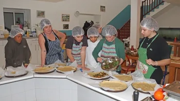En cuisine, un groupe d'enfants et leur animatrice mettent une préparation dans des fonds de tarte