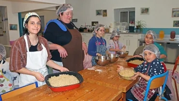 un goupe d'enfants et leurs animatrices portent des charlottes et des tabliers montrent leurs plats