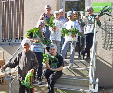 Un groupe d'enfants et leur animatrice montrent les légumes qu'ils viennent de récolter