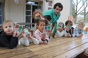 un groupe d'enfants et leur animateur montre des carrés segmentés en 4 couleurs