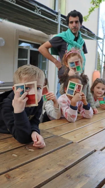 un groupe d'enfants et leur animateur montre des carrés segmentés en 4 couleurs
