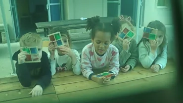 Photo prise avec un filtre vert davant l'objectif : un groupe d'enfants et leur animateur montre des carrés segmentés en 4 couleurs