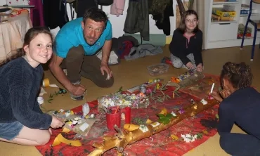 Un groupe d'enfants et leur animateur sont au sol avec plein d'éléments naturels