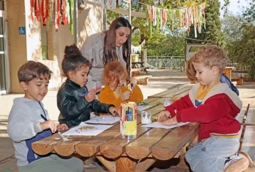 un groupe d'enfants et leur animatrice collent des morceaux de feuilles sur des dessins de hérissons