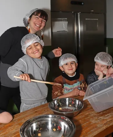 un groupe d'enfants et leur animatrice sont en cuisine avec des saladiers