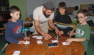 un groupe d'enfants et leur animateur manipulent des petites éoliennes et des panneaux photovoltaïques
