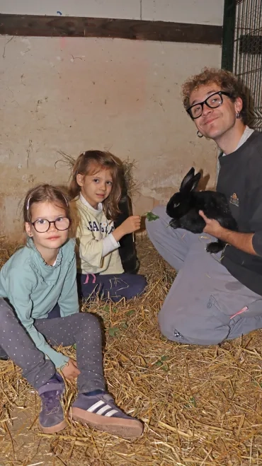 un animateur et deux enfant observent un lapin