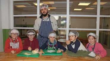 un groupe d'enfants et leur animateur coupent des oignons et du fromage