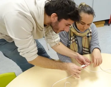 L'animateur aide la participante à réaliser un nœud plat