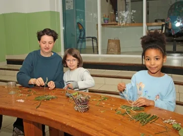 deux enfants et leur animatrice découpent des éléments naturels