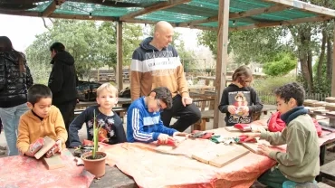 un groupe d'enfants et leur animateur poncent des morceaux de bois