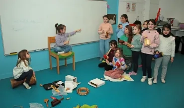 un groupe d'enfants et leur animatrice manipulent différents instruments de musique