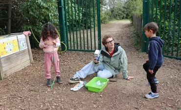 deux enfants et leur animateur observent des types de déchets devant les poubelles