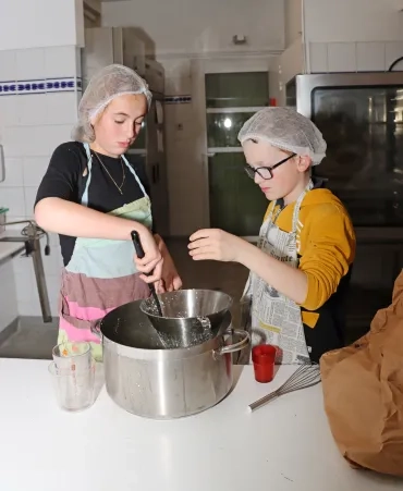 deux enfants écrasent du caillé en cuisine