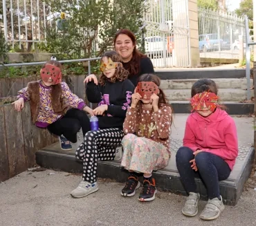 un groupe d'enfants et leur animatrice portent des masques colorés en carton 