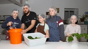 un groupe d'enfants et leur animateur essorent des blettes en cuisine