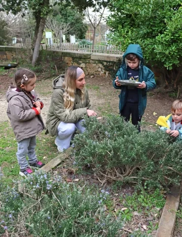 un groupe d'enfants et leur animatrice coupent du romarin