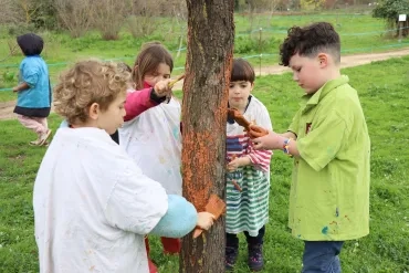 Un groupe d'enfants peint un tronc d'arbre avec de l'argile