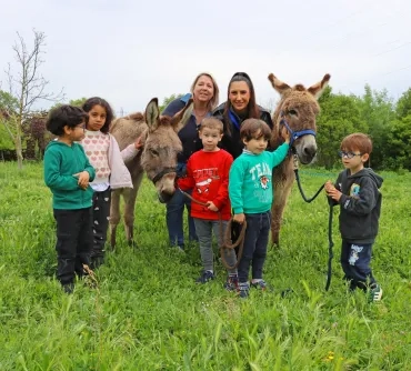 Un groupe d'enfants et leurs animatrices posent entre deux ânes
