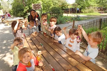 Un groupe d'enfants et leur animatrice montrent des pots en terre décorés