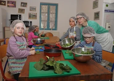 Un groupe d'enfants et leur animatrice en cuisine montrent le légumes découpés