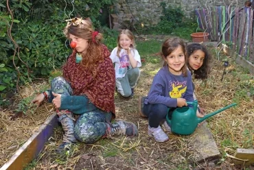 Un groupe d'enfants et leur animatrice jardinent