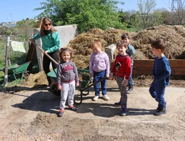 Un groupe d'enfants et leur animatrice posent devant l'aire de compostage