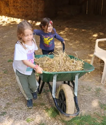 deux enfants transportent de la paille dans une brouette