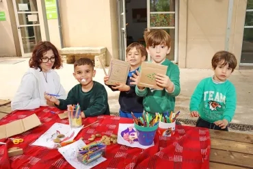 Un groupe d'enfants et leur animatrice montrent des carrés de carton
