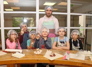 Un groupe d'enfants et leur animateur posent en cuisine avec de la pâte