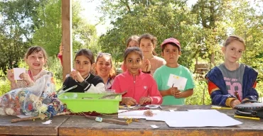 Un groupe d'enfants et leur animatrice montrent des morceaux de bois et du papier