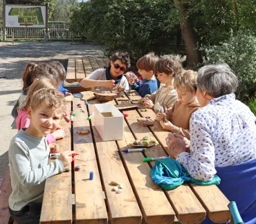 Un groupe d'enfants et leur animatrice dessinent sur des cailloux