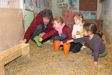 Un groupe d'enfants et leur animateur sont accroupis dans un enclos