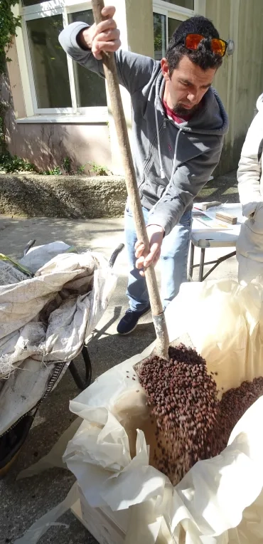 Un participant met du gravier au fond de la jardinière.