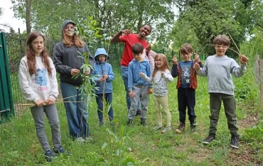 Un groupe d'enfants et leur animateur montrent des branches d'osier