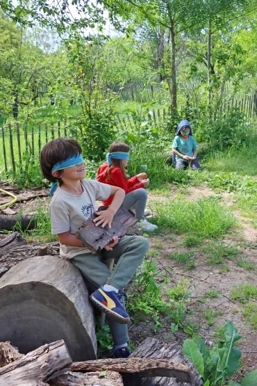 trois enfant les yeux bandés touchent des éléments naturels