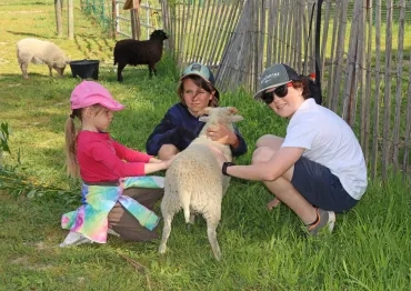 trois enfant câlinent un agneau