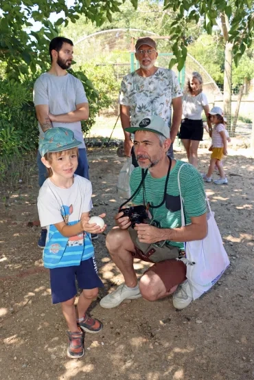 un enfant à côté de son papa montre un oeuf d'oie