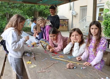 Un groupe d'enfants et leur animatrice manipulent de la laine