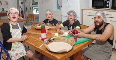 une groupe d'enfants et leur animateurs tiennent des oignons en cuisine